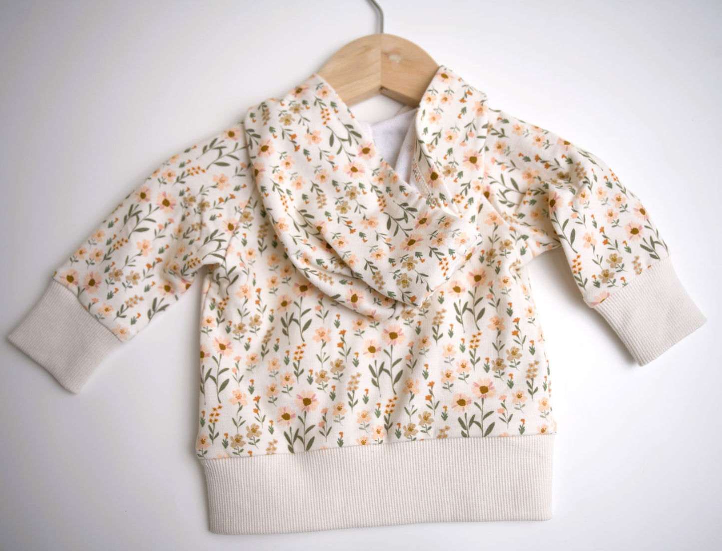 Babysprouts girl's hooded jacket with a floral daisy pattern in various colors primarily in white and pink, with a drawstring hood.