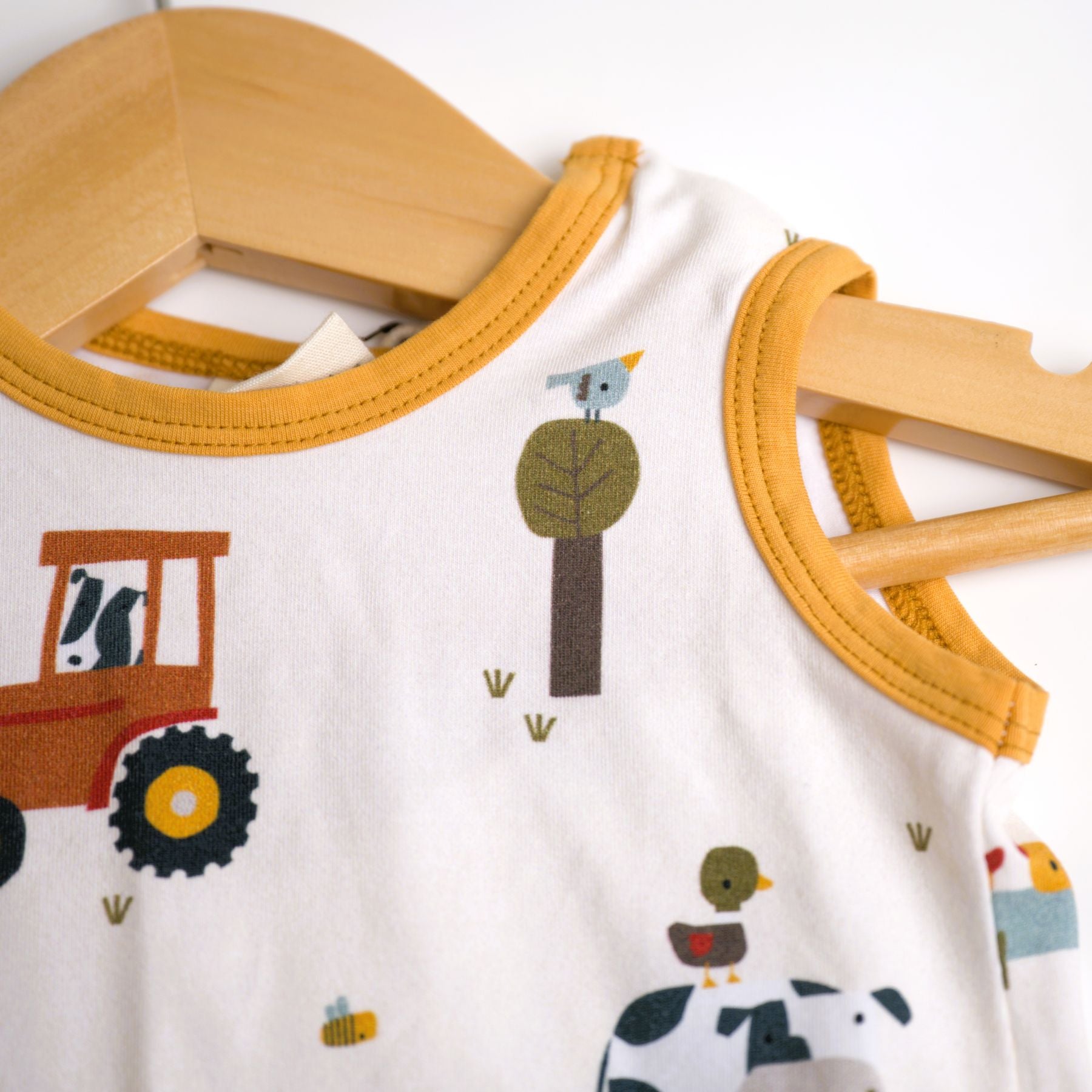 Viverano Organics baby playsuit set with a farm animal print, including a sleeveless tee and shorts in orange, with a white sash tie at the waist.