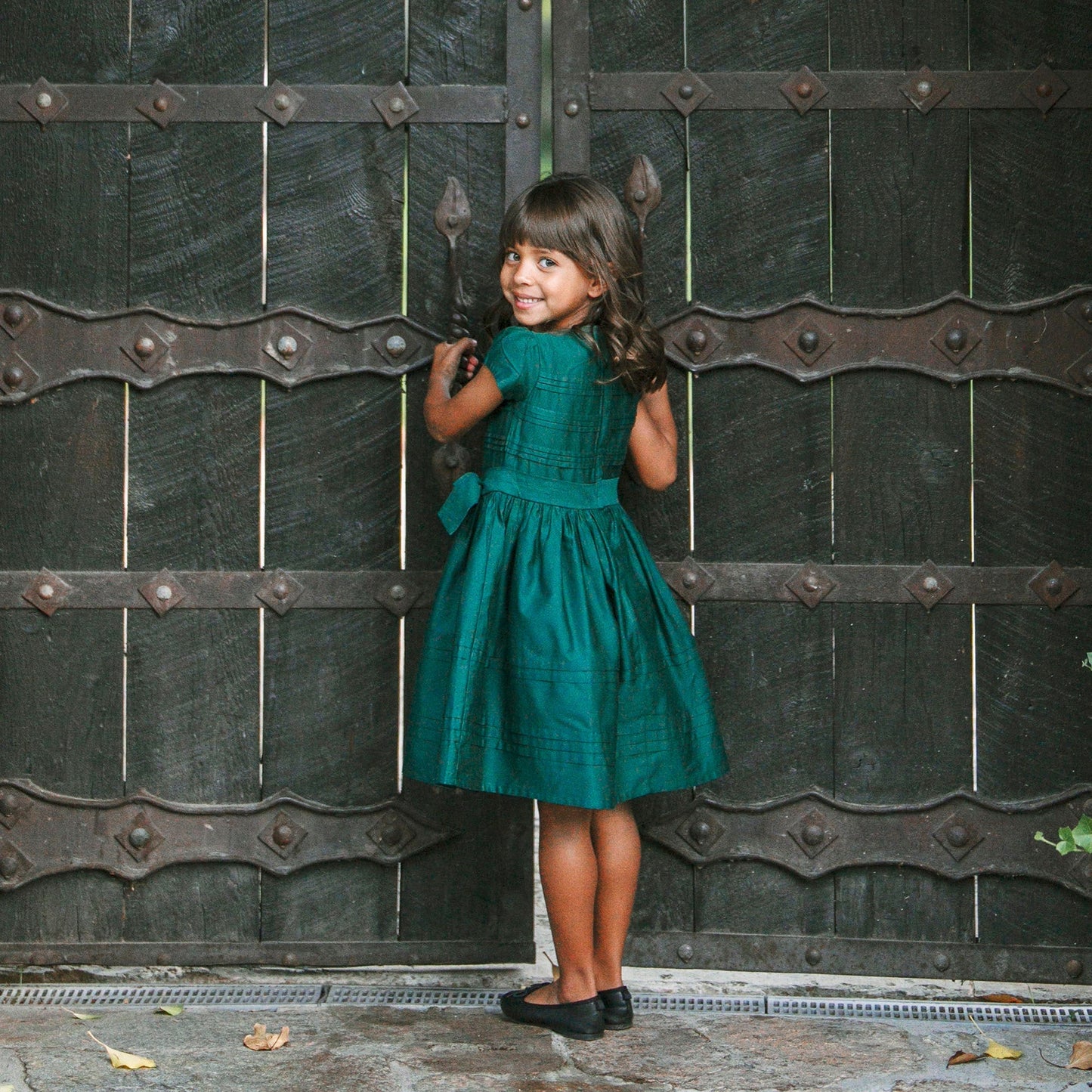 girl wearing sustainable Christmas dress for girls in green sateen