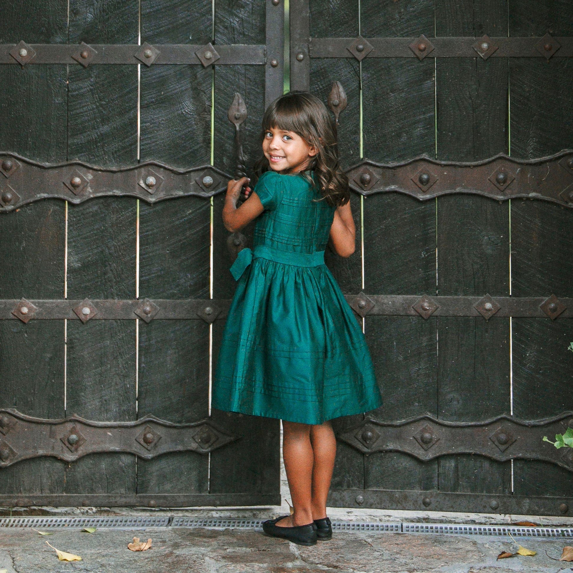 girl wearing sustainable Christmas dress for girls in green sateen