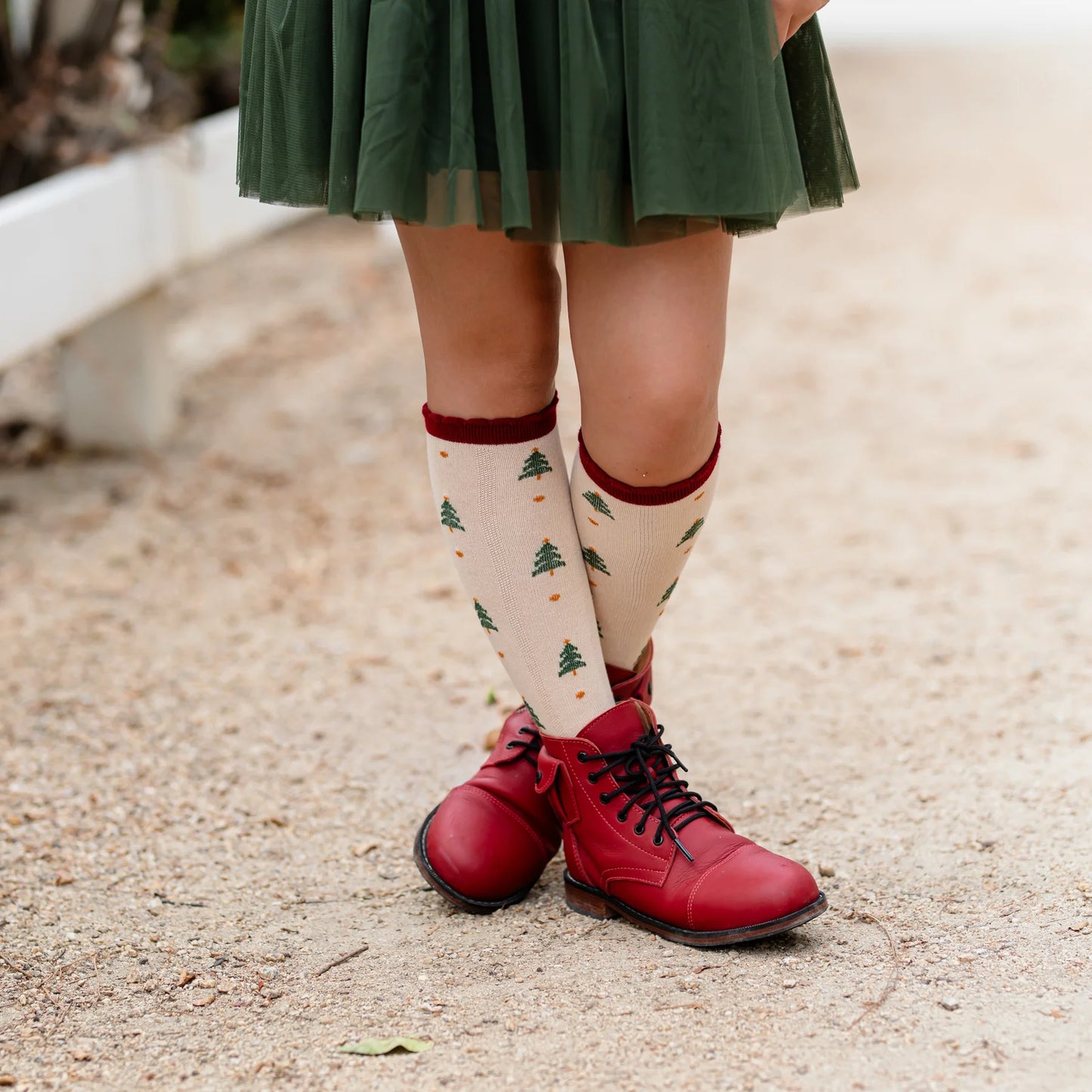 Person wearing red shoes and patterned tree socks on a gravel surface