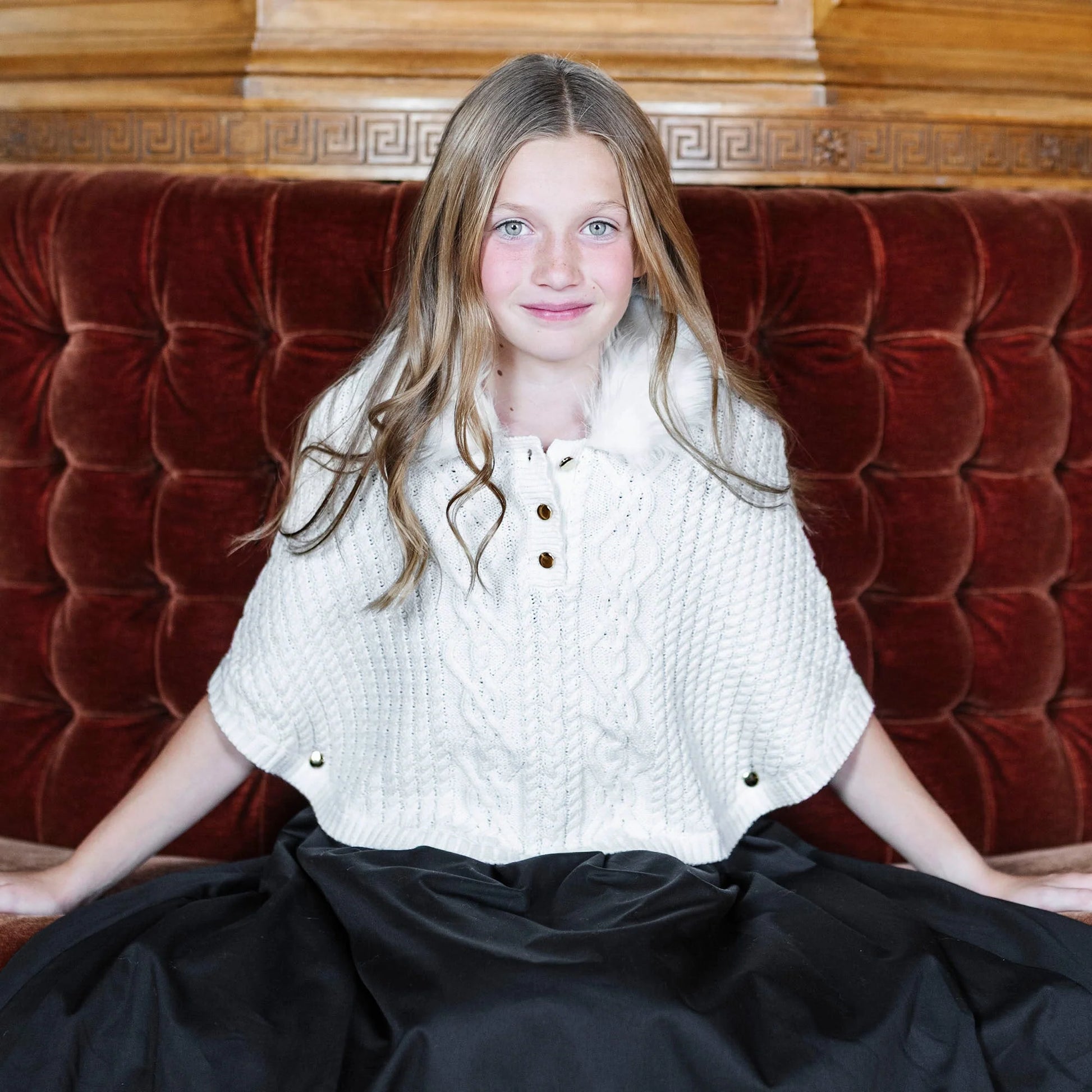 young girl wearing Hope & Henry organic white cable sweater cape with faux fur collar